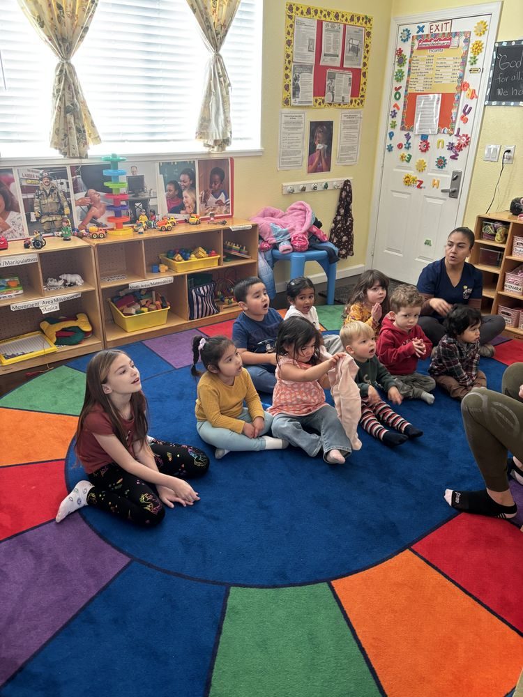 Children sitting on the colorful circle-time rug in the classroom